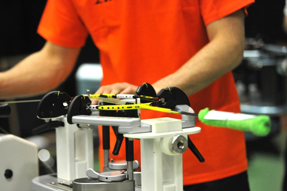 Nahaufnahme einer Person, die einen Tennisschläger auf einer Besaitungsmaschine vorbereitet.