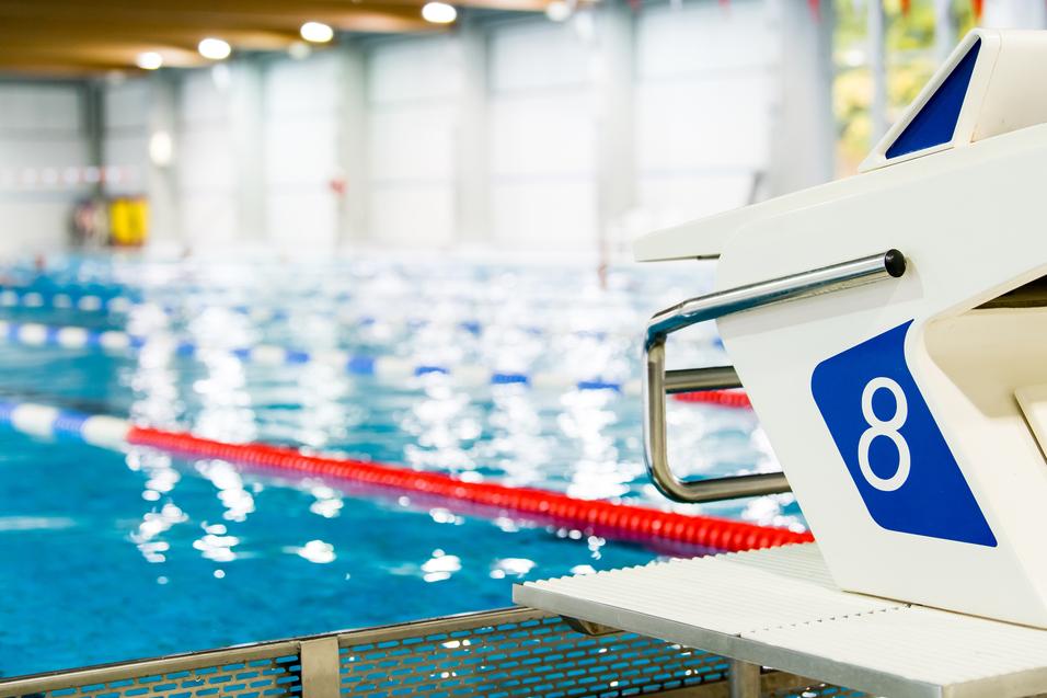 Startblock Nummer 8 an einem Schwimmbecken mit blauen Wasser und Schwimmbahnen im Hintergrund.